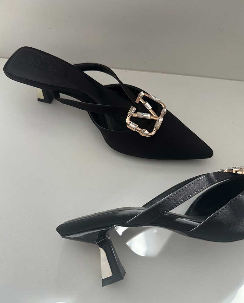 Μαύρο Mule από ύφασμα, με ιδιαίτερο κοντό τακουνάκι με λεπτομέρεια χρυσή και αγκράφα με στρας, ιδανικό για καθημερινές αλλά και βραδινές εξόδους.